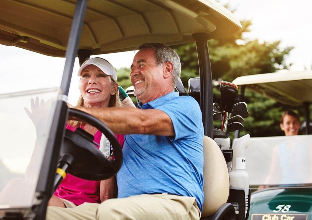 couple driving golf cart on golf course